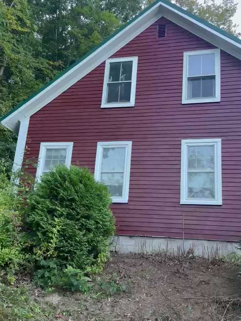 After: Clapboard farmhouse in deep red with white window trim