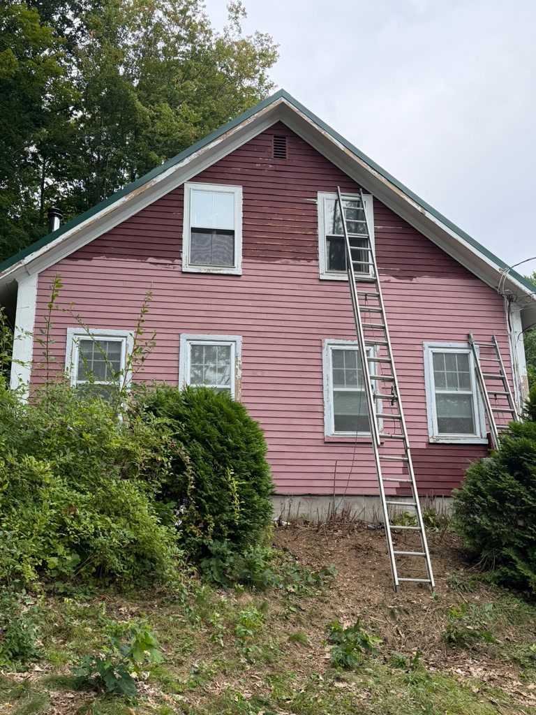 Before: Clapboard farmhouse in deep red with white window trim