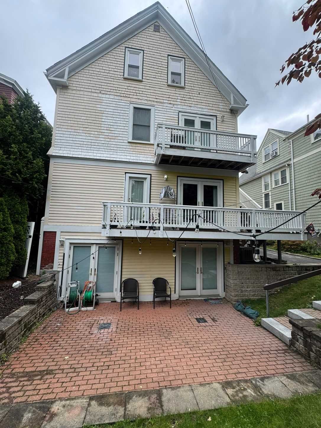 Before: Rear of a three-story house with stacked porches and stairs